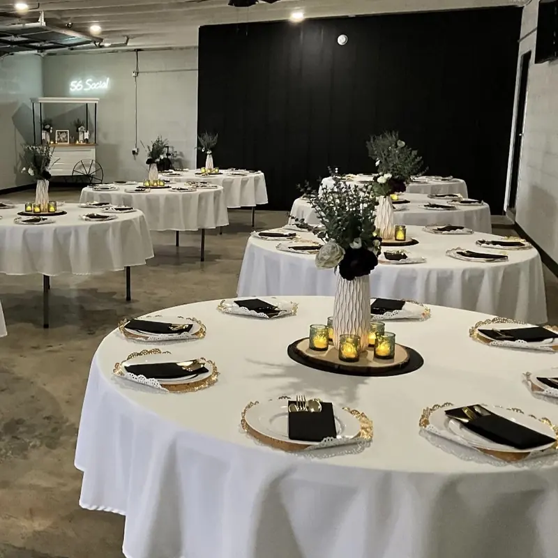 White linens with gold chargers, black napkins and candlelit centerpieces