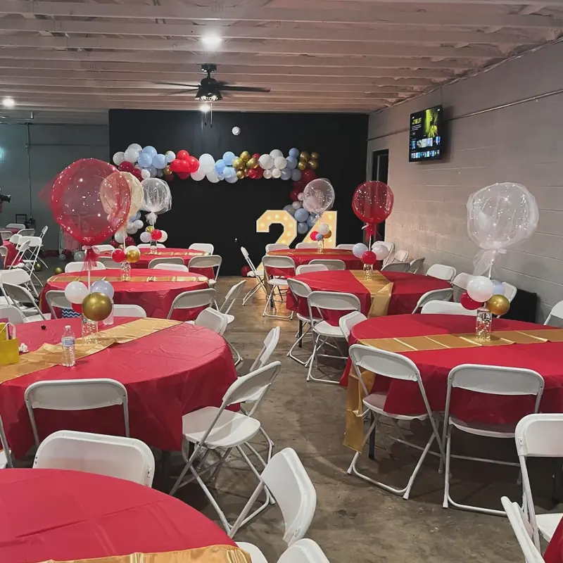 Red tables with gold runners and a 21st birthday balloon wall
