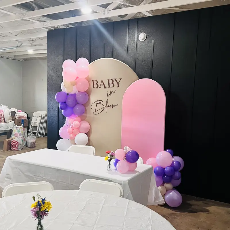 A Baby in Bloom backdrop with purple and pink balloons