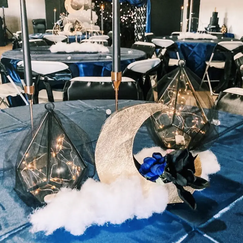 A navy table with a moon centerpiece and glowing lanterns