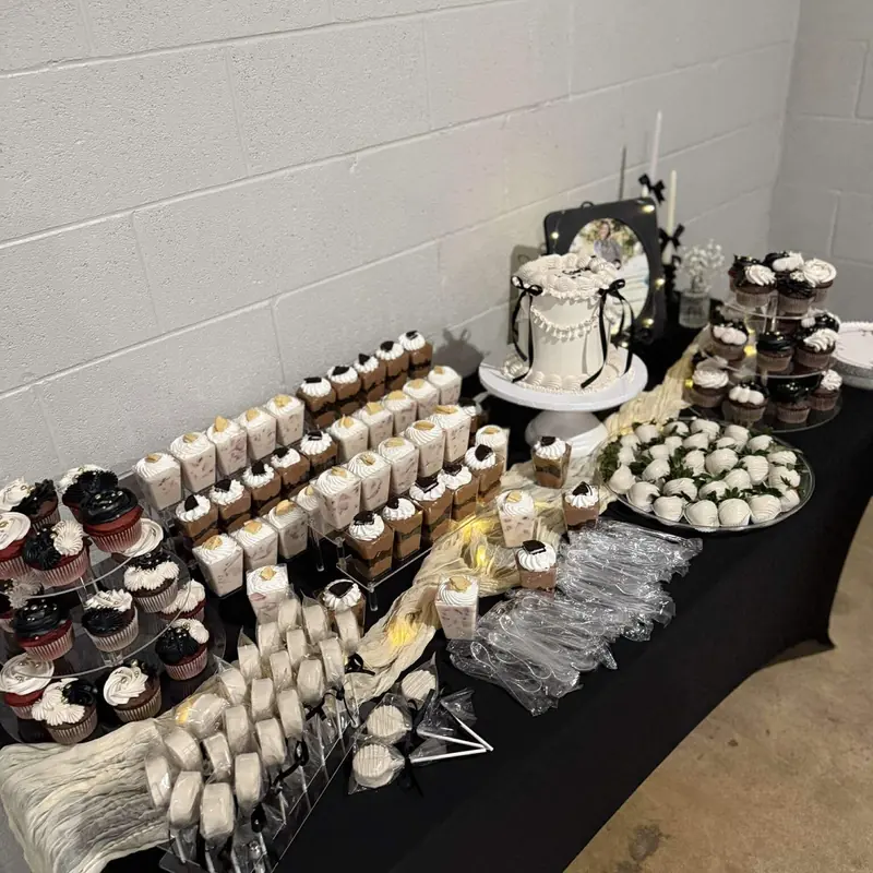 A black and white dessert table with cupcakes and a tiered cake