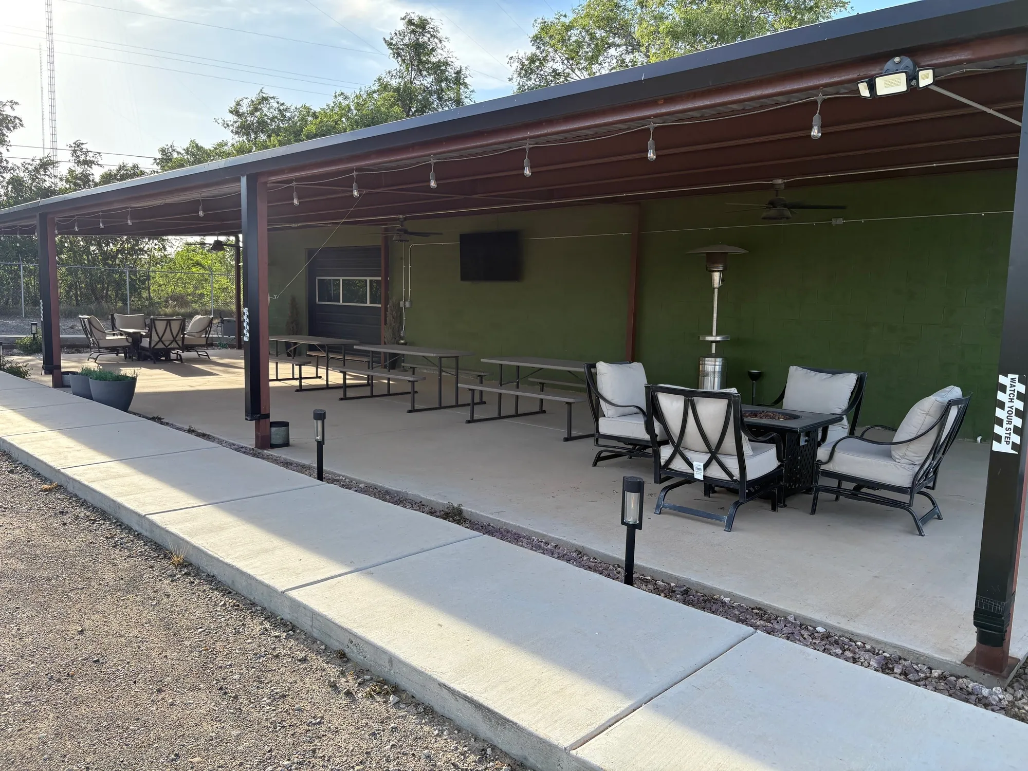 Covered patio with picnic tables, lounge chairs and an outdoor TV